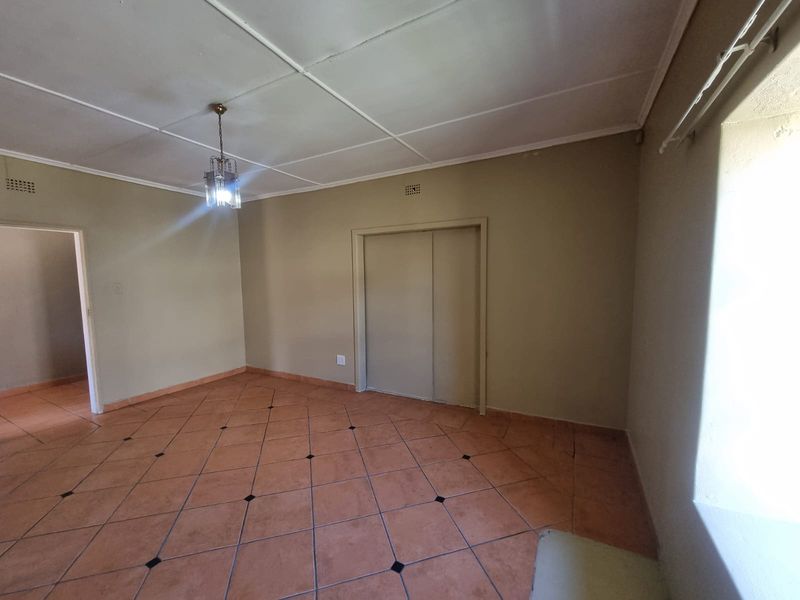 An empty bedroom featuring tiled flooring, a built-in wardrobe, and a standard ceiling, offering a blank canvas for renovation or restyling.