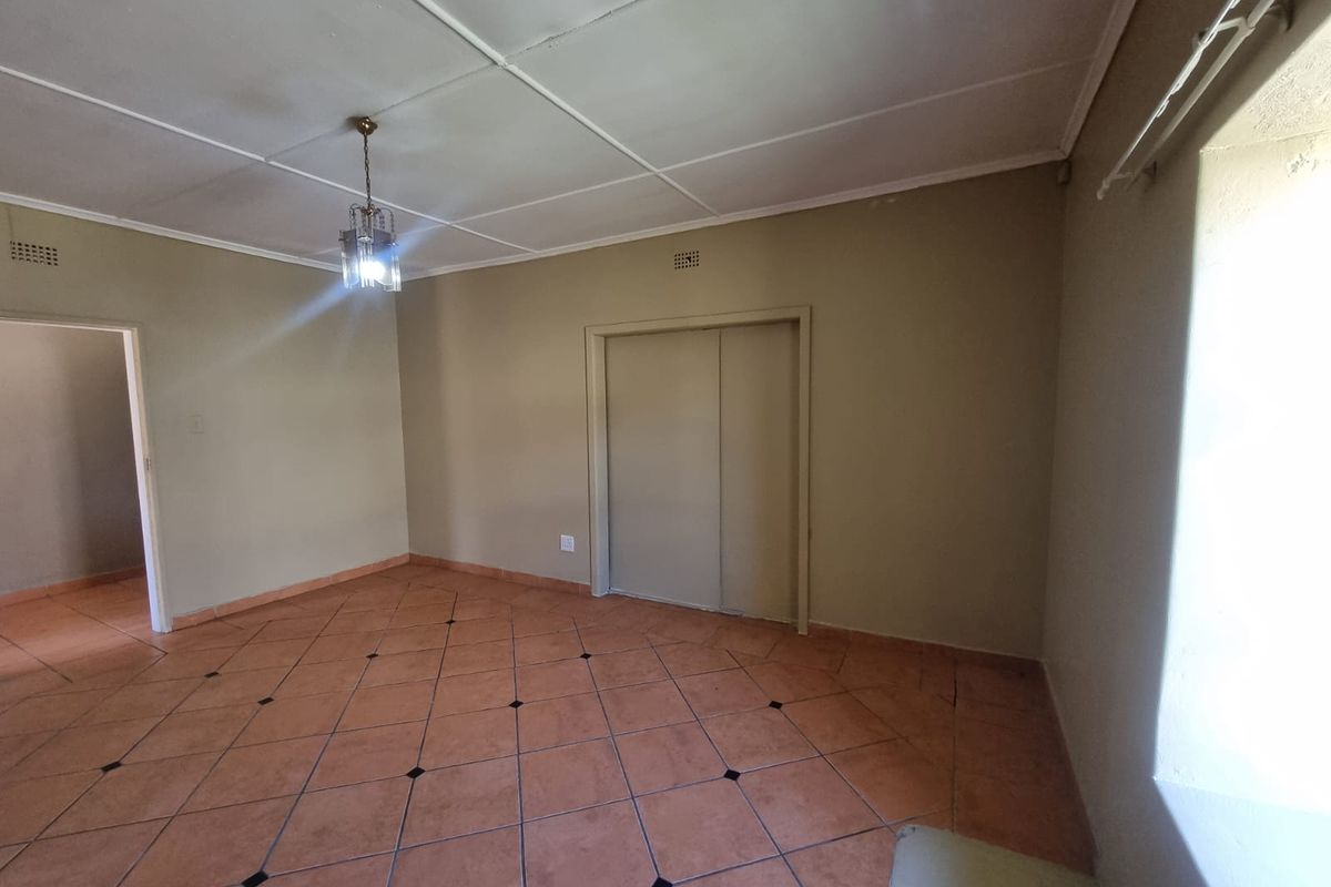 An empty bedroom featuring tiled flooring, a built-in wardrobe, and a standard ceiling, offering a blank canvas for renovation or restyling.