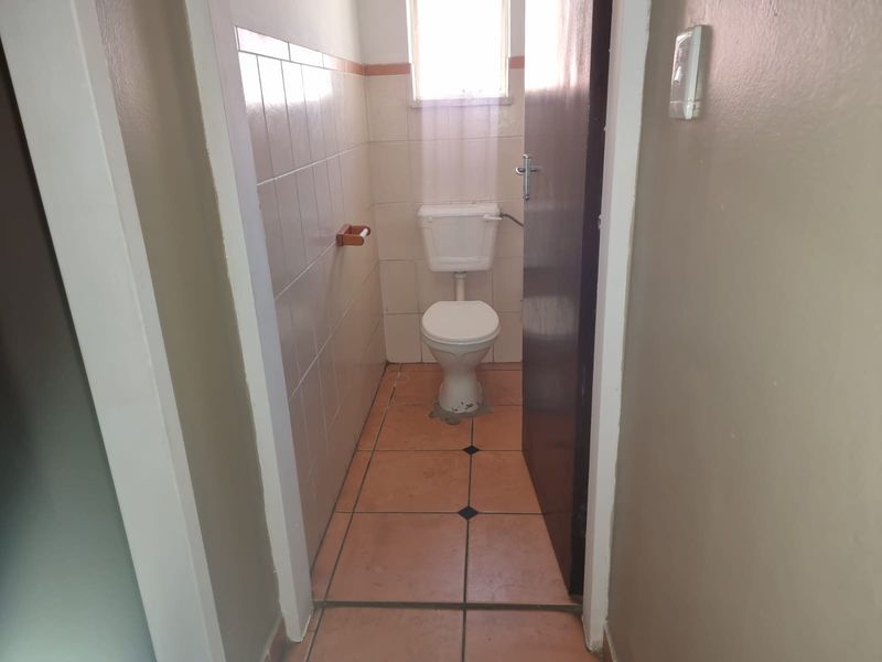 A compact, functional guest toilet featuring ceramic wall and floor tiles, providing a simple and practical layout.