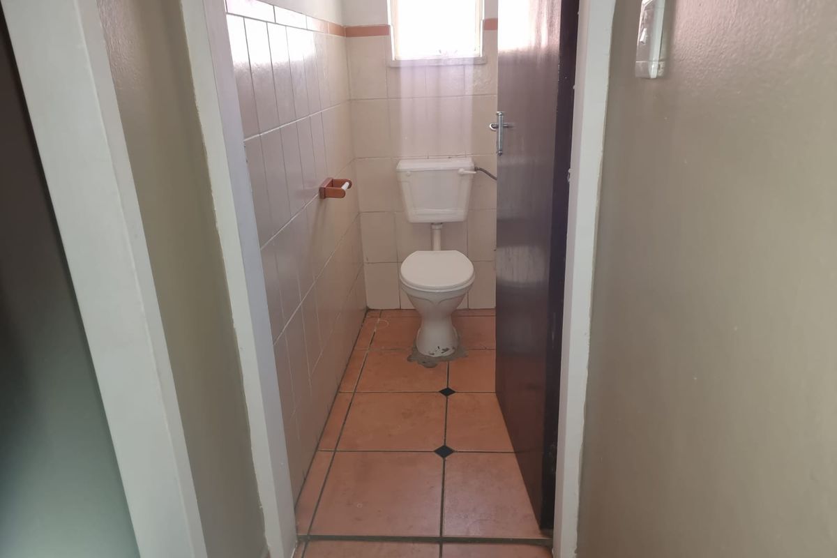A compact, functional guest toilet featuring ceramic wall and floor tiles, providing a simple and practical layout.