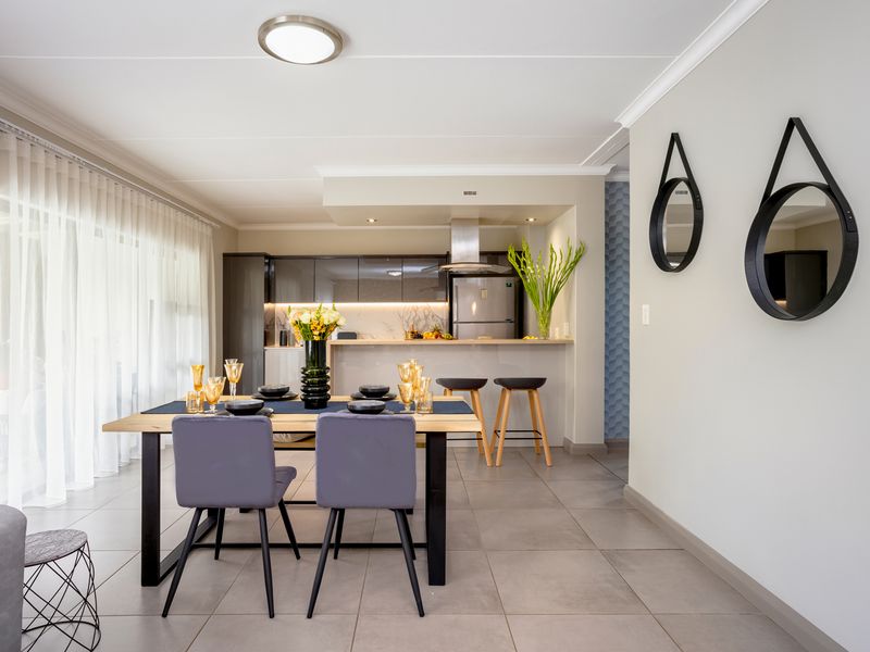 Modern open-plan living and dining area featuring sleek kitchen cabinetry, a breakfast bar, and large sliding doors leading to an outdoor space.