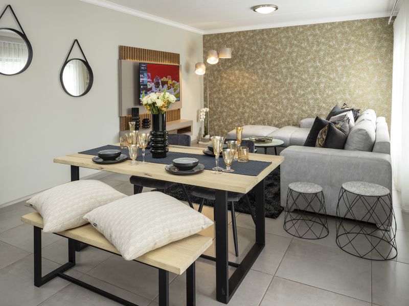 A well-presented open-plan living and dining area featuring modern tiled flooring, a decorative feature wall, and a built-in media console.