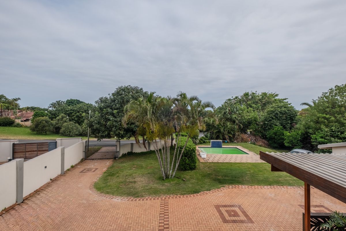 Elevated view of the property grounds featuring a paved driveway, landscaped garden, and a swimming pool area.