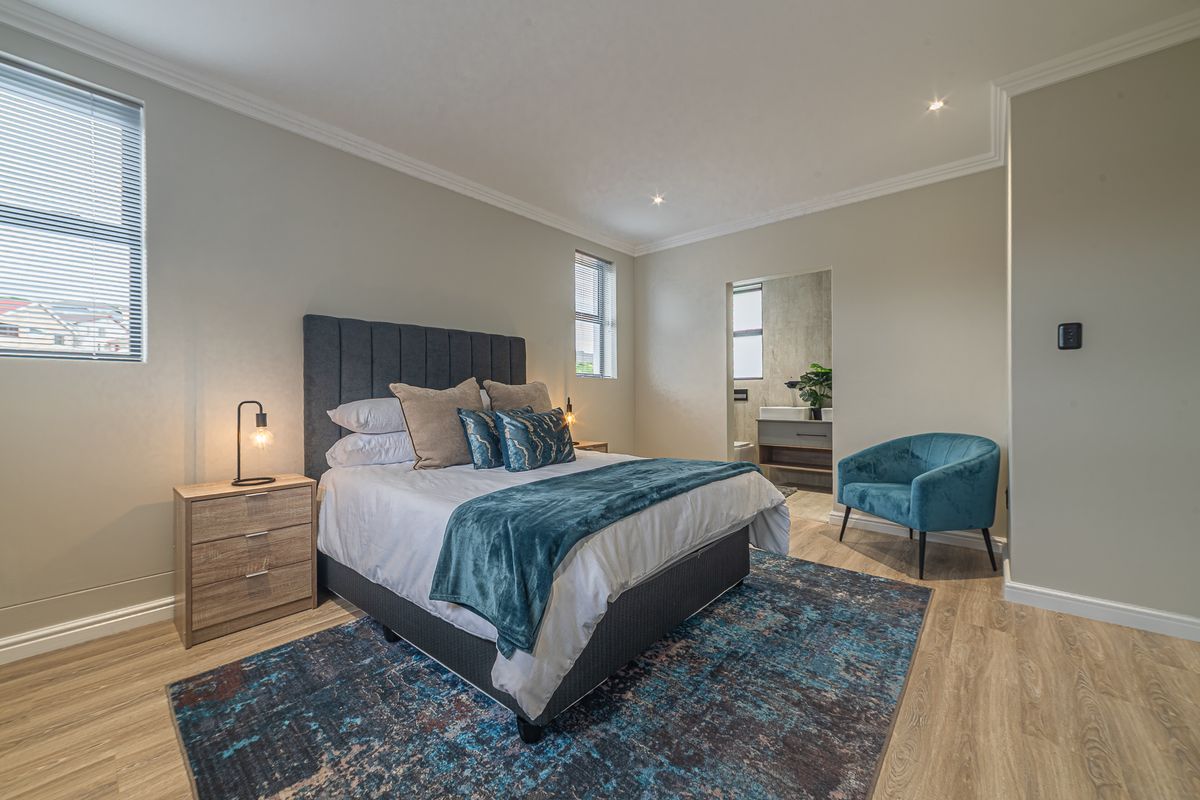 A well-maintained bedroom featuring modern laminate flooring, recessed downlighting, decorative cornicing, and direct access to an en-suite bathroom.