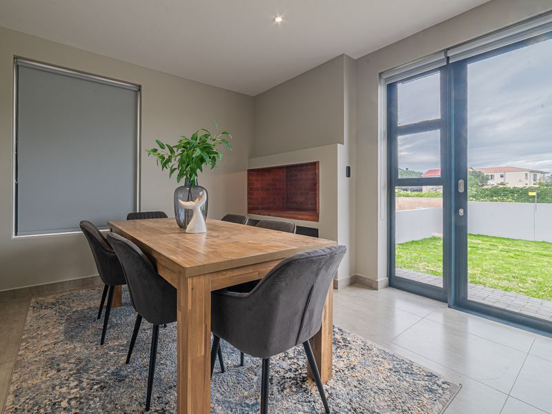 A bright dining area featuring a built-in fireplace, tiled flooring, and large sliding glass doors providing direct access to the rear garden.