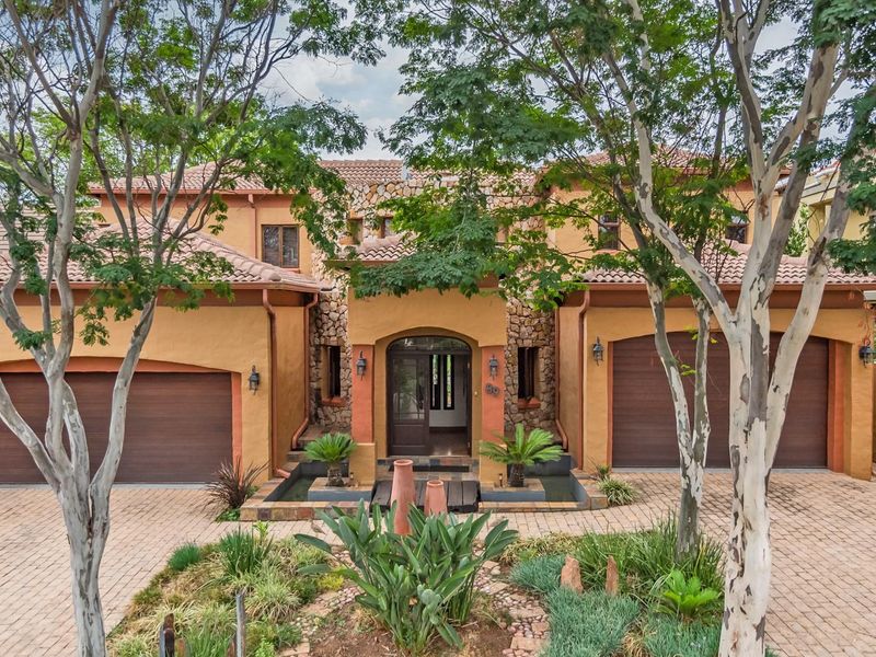 A well-maintained double-storey residence featuring a paved driveway, double garage, stone-clad facade, and an inviting entrance with a decorative water feature.