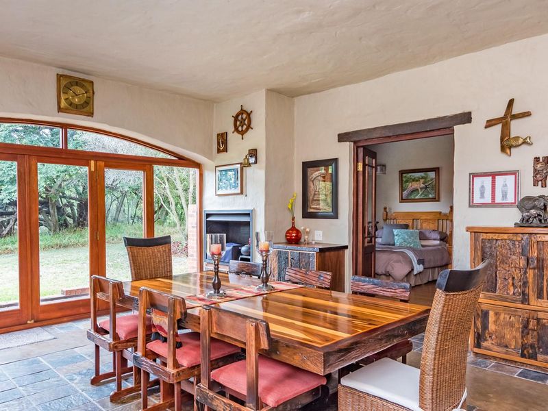 Spacious dining room featuring slate tile flooring, a built-in fireplace, and large timber-framed folding doors providing direct access to the garden.