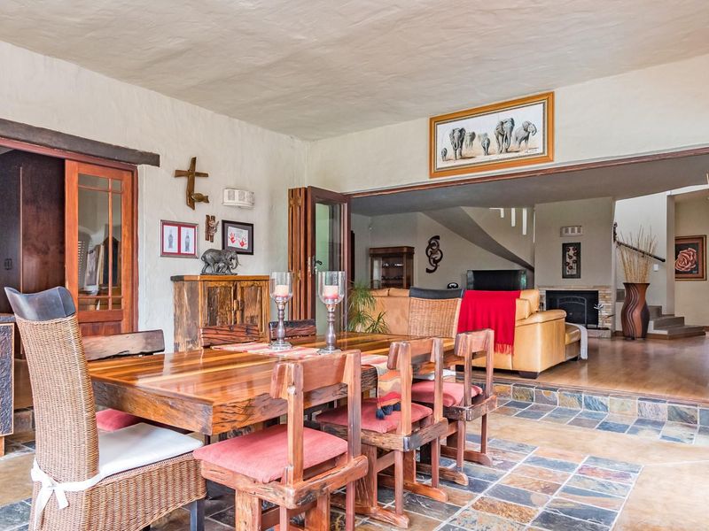 Spacious open-plan dining and living area featuring rustic slate tile flooring, bi-fold doors leading to the exterior, and a cozy fireplace.