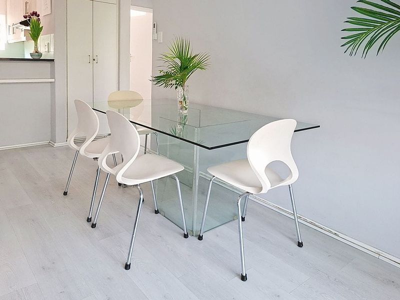 A bright dining area featuring light-toned laminate flooring and a built-in storage cupboard, offering a clean and neutral space for meals.