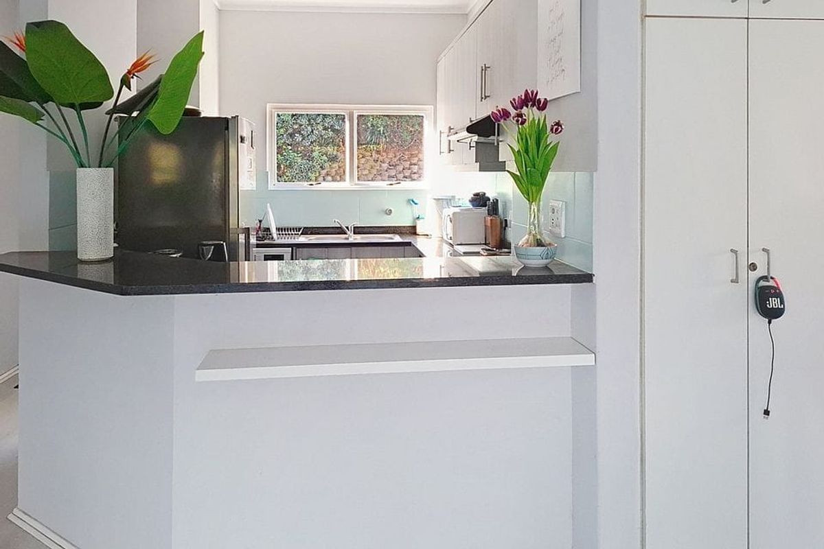 A functional kitchen featuring granite countertops, ample built-in cabinetry, a tiled backsplash, and a convenient built-in pantry cupboard.