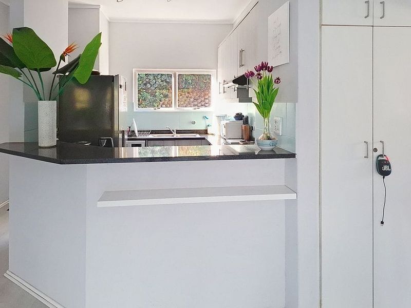 A functional kitchen featuring granite countertops, ample built-in cabinetry, a tiled backsplash, and a convenient built-in pantry cupboard.
