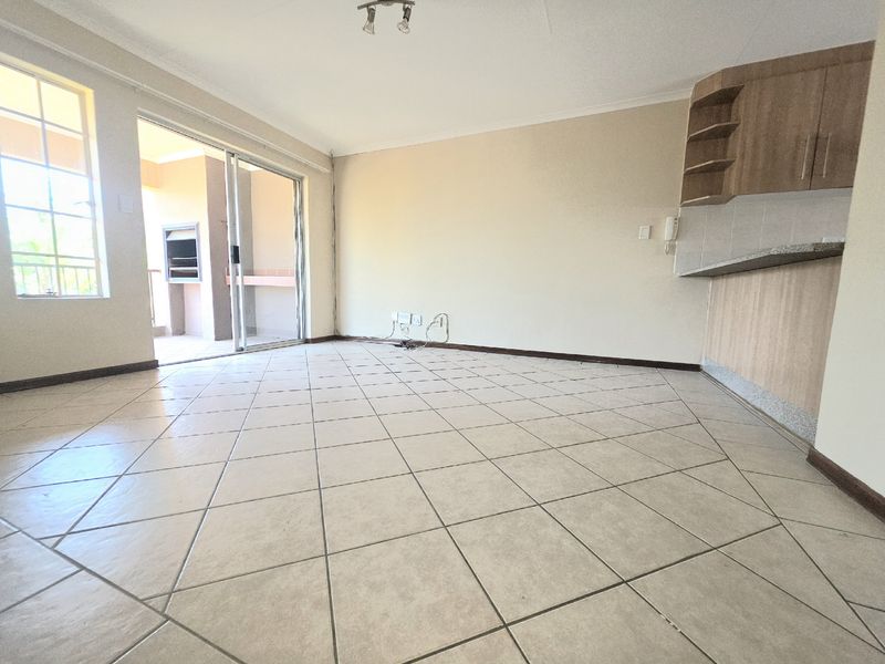 Spacious open-plan living area featuring tiled flooring, built-in kitchen cabinetry with granite countertops, and direct access to a private balcony.