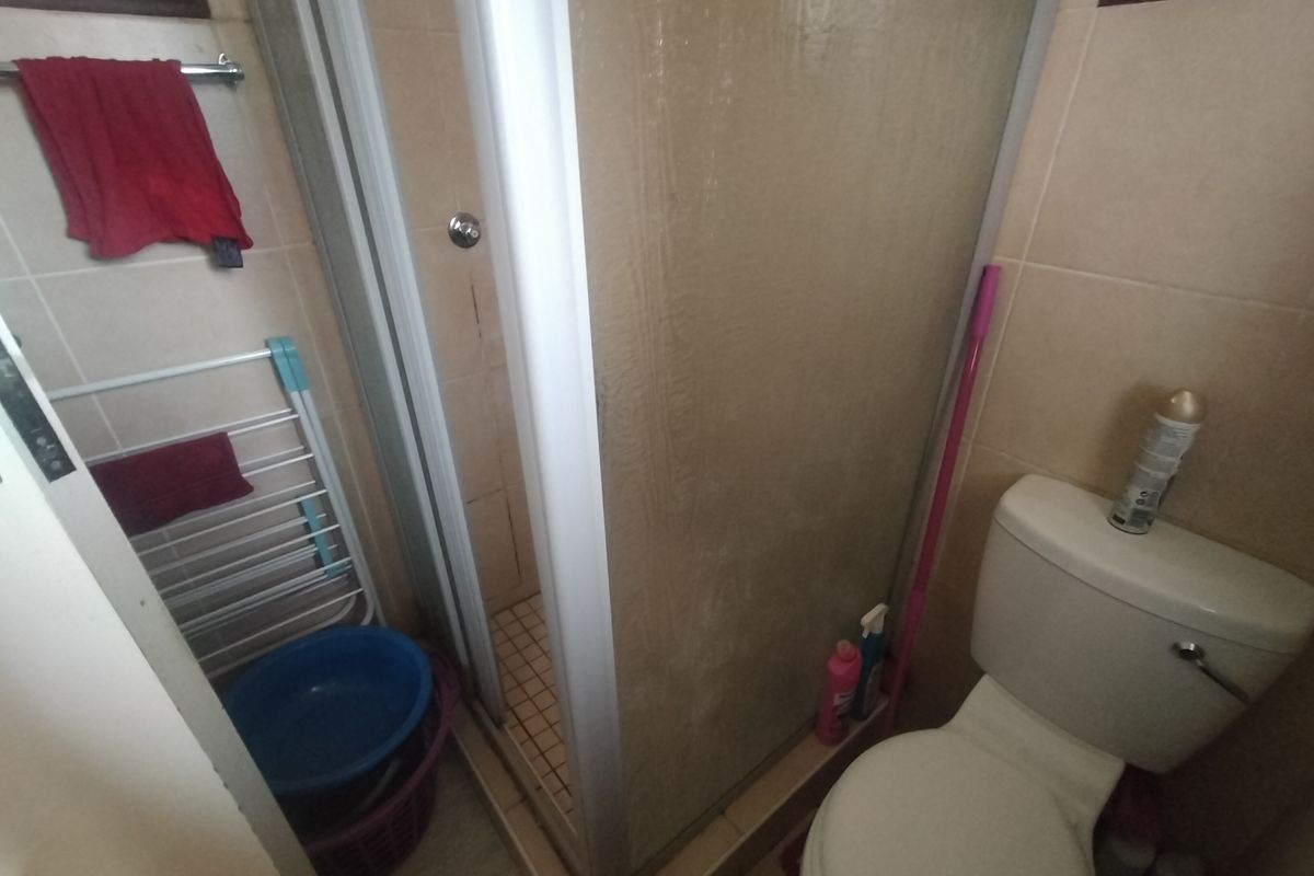 A compact bathroom featuring a shower enclosure and a standard toilet with tiled finishes throughout.