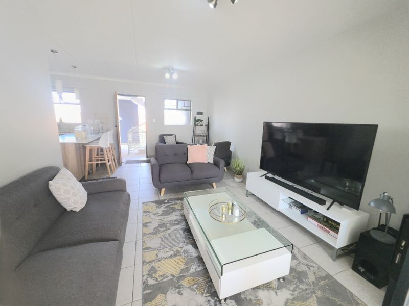An open-plan living area featuring tiled flooring and a kitchen breakfast bar, creating a functional and connected space for daily living.