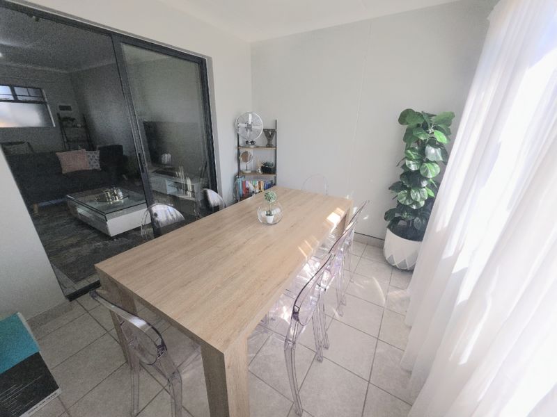 A bright dining area featuring neutral tiled flooring and a large sliding glass door providing access to the adjacent living space.