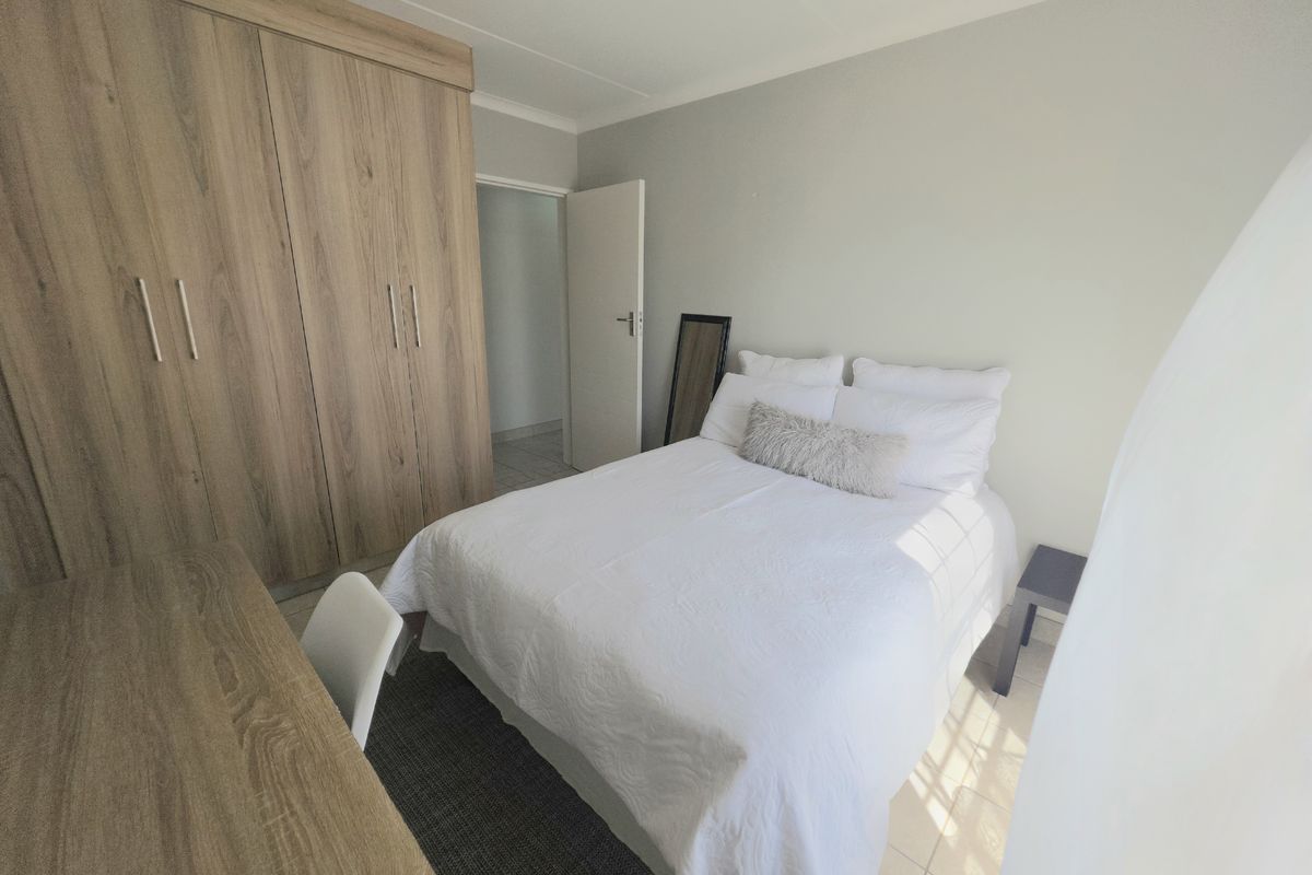 A well-maintained bedroom featuring neutral walls, tiled flooring, and ample built-in cupboard storage space.
