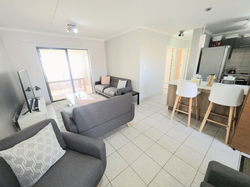 Open-plan living area featuring tiled floors, a kitchen island with breakfast bar seating, and a sliding glass door leading to the patio.