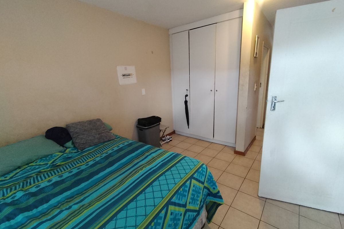 A bedroom featuring tiled flooring and a built-in wardrobe with white doors.