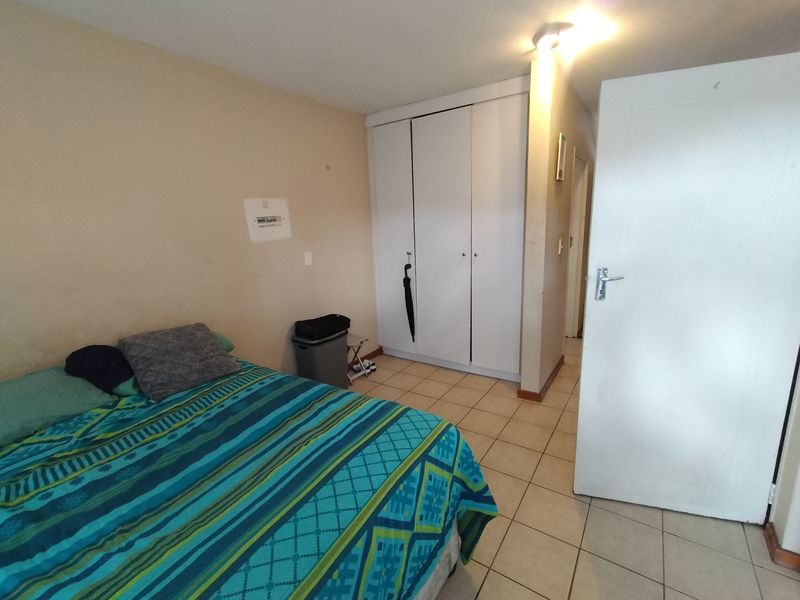 A functional bedroom featuring tiled flooring and built-in cupboards, offering a neutral base for personalization.