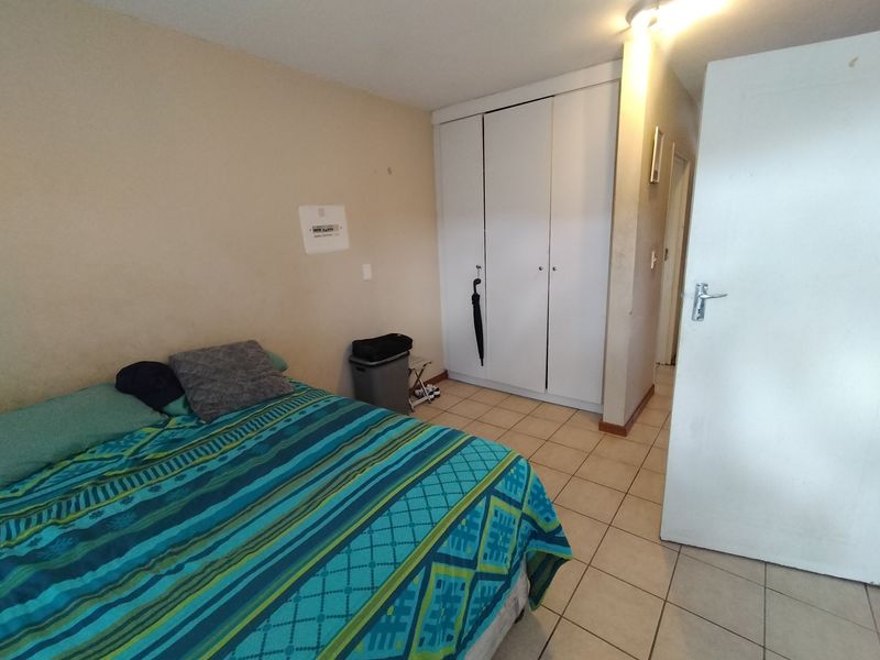 A functional bedroom featuring tiled flooring and built-in cupboards, offering a neutral base for potential interior updates.