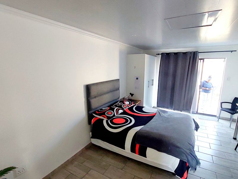 A bedroom featuring tiled flooring, a built-in wardrobe, and a sliding glass door providing access to an outdoor area.