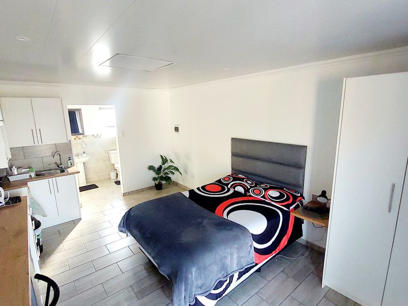 Open-plan studio apartment featuring a compact kitchen area, tiled flooring, and a built-in wardrobe, with an adjoining bathroom.