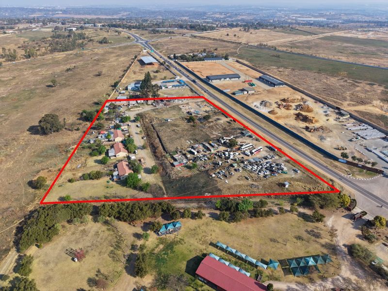 Aerial view of a large, undeveloped plot of land with existing structures, clearly demarcated by red boundary lines.