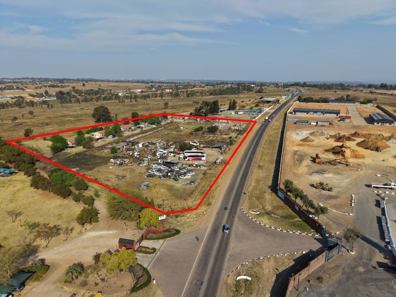 Aerial view of a large, undeveloped plot of land with road frontage, suitable for commercial or industrial development.