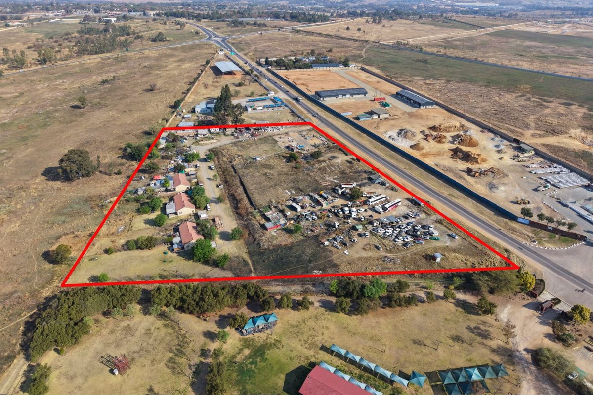 Aerial view of a large, undeveloped plot of land with existing structures, clearly demarcated by red boundary lines.