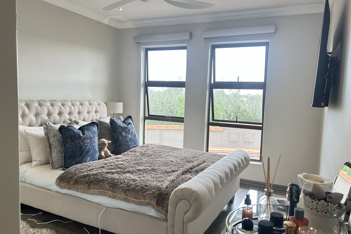 A well-maintained bedroom featuring laminate flooring, recessed lighting, a ceiling fan, and large windows providing natural light.