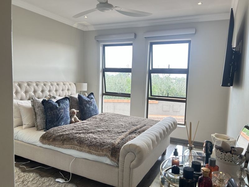 A well-maintained bedroom featuring laminate flooring, recessed lighting, a ceiling fan, and large windows providing natural light.