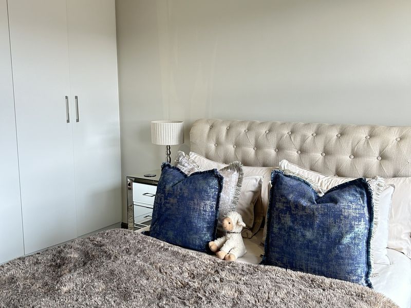 A well-maintained bedroom featuring neutral walls, crown molding, recessed lighting, and ample built-in cupboard storage.