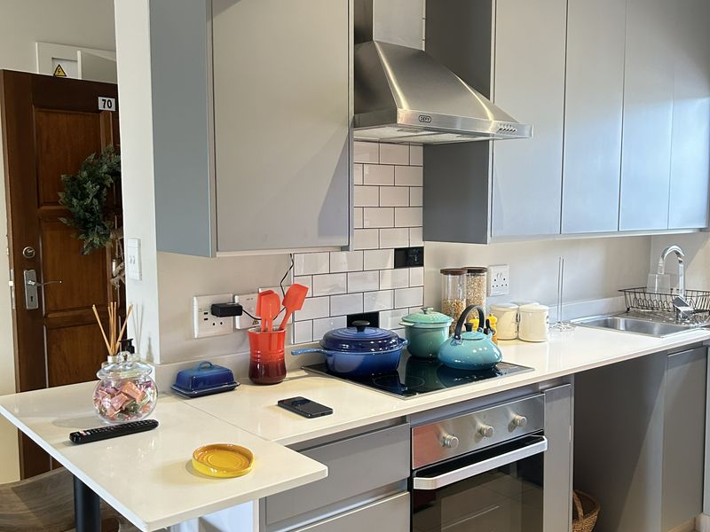 Modern kitchen featuring grey cabinetry, white quartz countertops, subway tile backsplash, integrated stainless steel appliances, and a convenient breakfast bar.