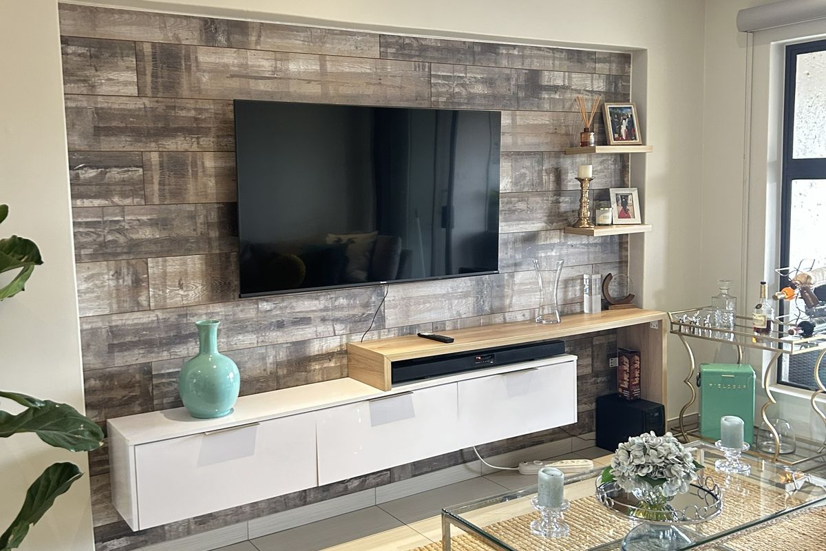 Modern living room featuring a custom built-in floating media console, wood-look feature wall, and recessed ceiling lighting.
