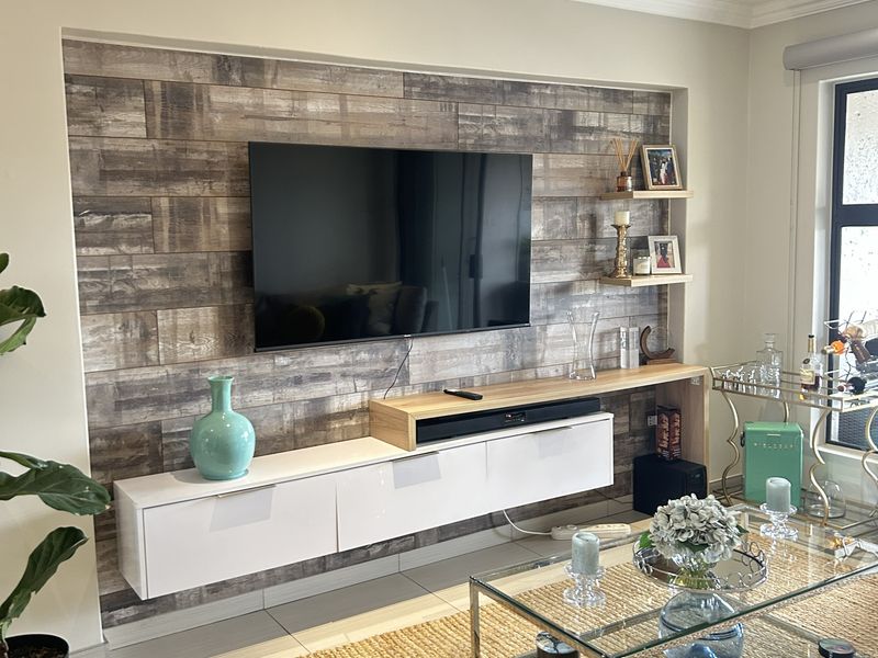 Modern living room featuring a custom built-in floating media console, wood-look feature wall, and recessed ceiling lighting.