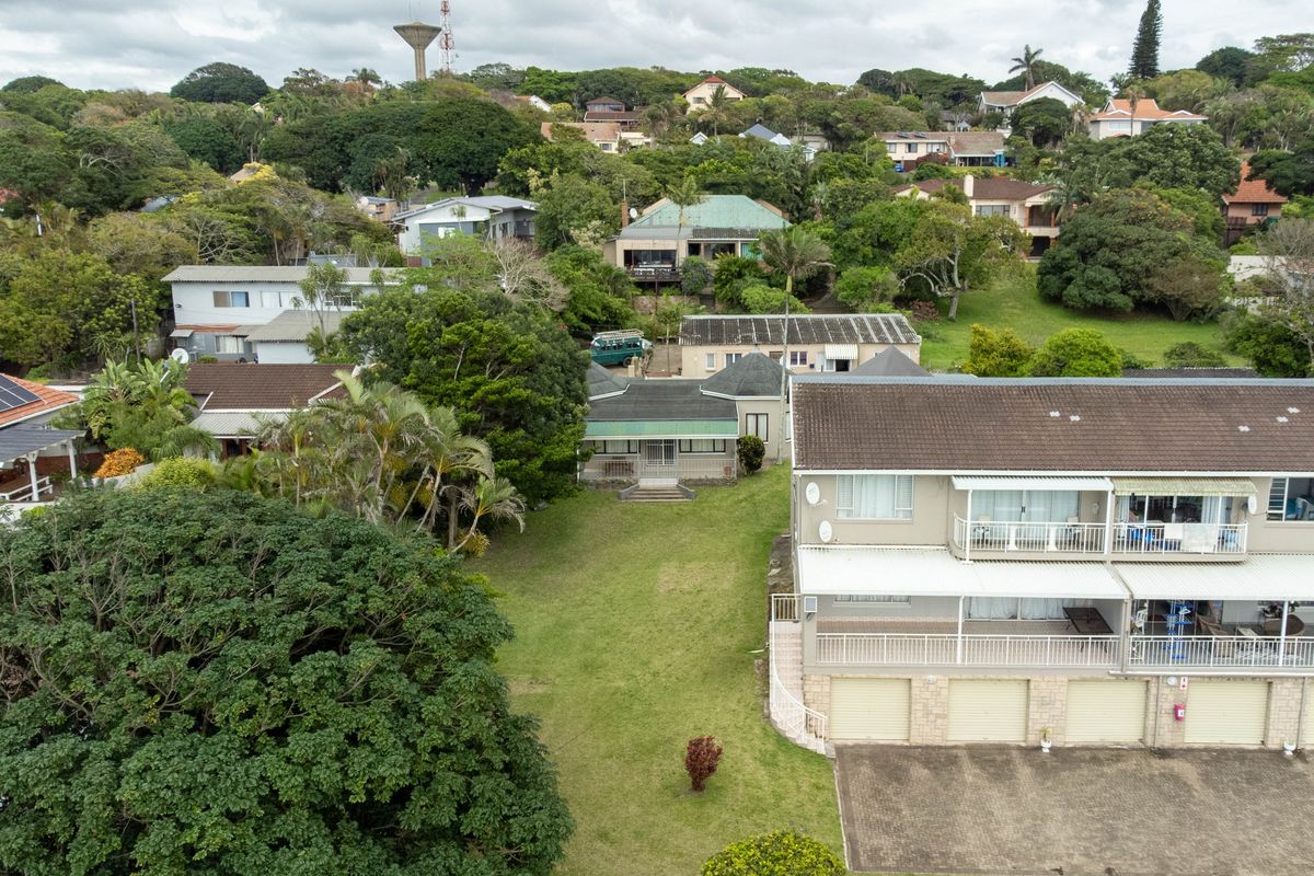 Aerial view of a residential townhouse complex featuring multi-level units with balconies, garages, and surrounding green space in a suburban setting.