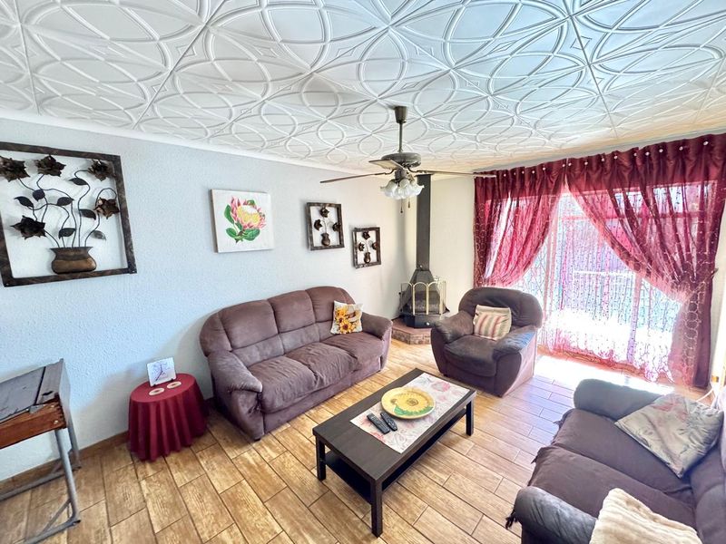 A comfortable living room featuring a decorative patterned ceiling, a freestanding fireplace, and tiled flooring with direct access to the outdoor area.
