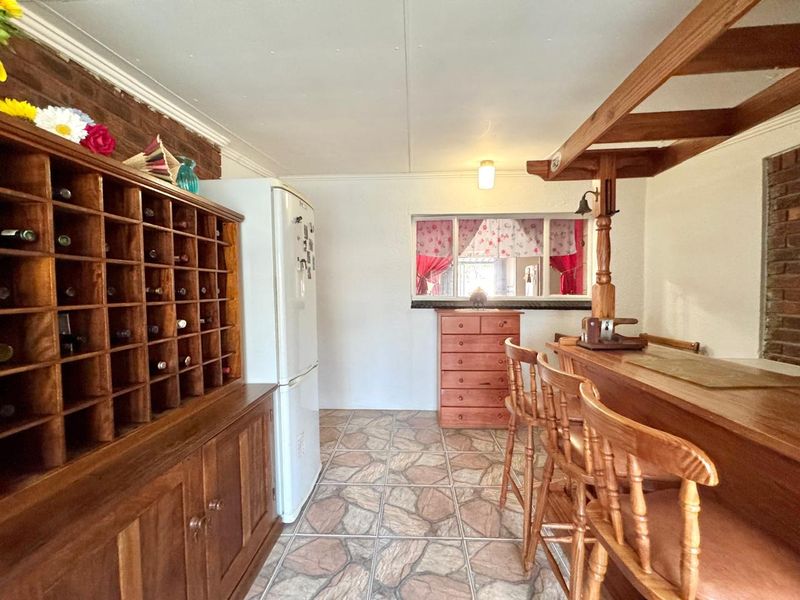 A dedicated bar area featuring a built-in wooden wine rack, a fixed bar counter, and rustic tiled flooring with exposed brick accents.