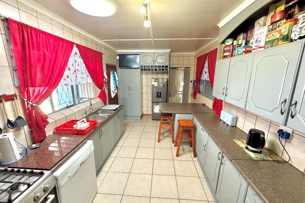 Functional kitchen featuring granite countertops, built-in cabinetry, gas hob, and tiled flooring, offering a practical layout for daily meal preparation.