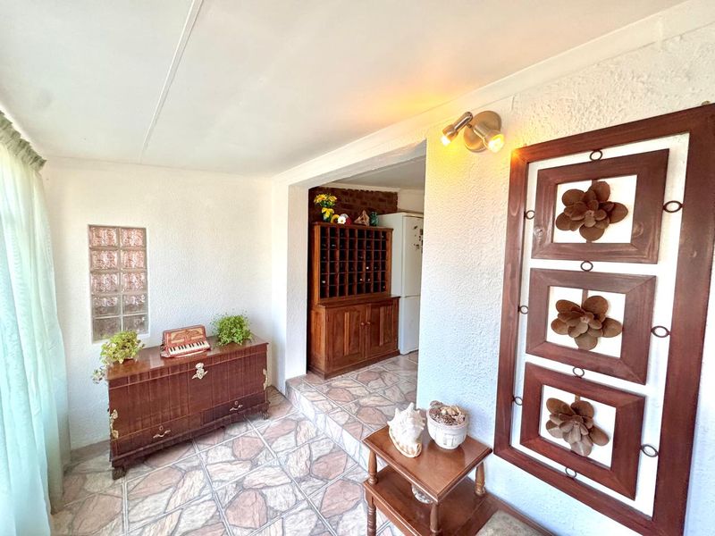 A tiled hallway area featuring a glass block window and wall-mounted lighting, leading through to an adjacent room.