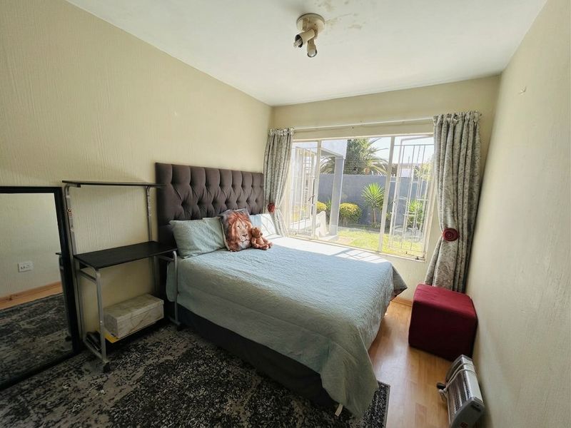 A bedroom featuring laminate flooring and a sliding glass door providing access to the garden, with visible signs of ceiling water damage.