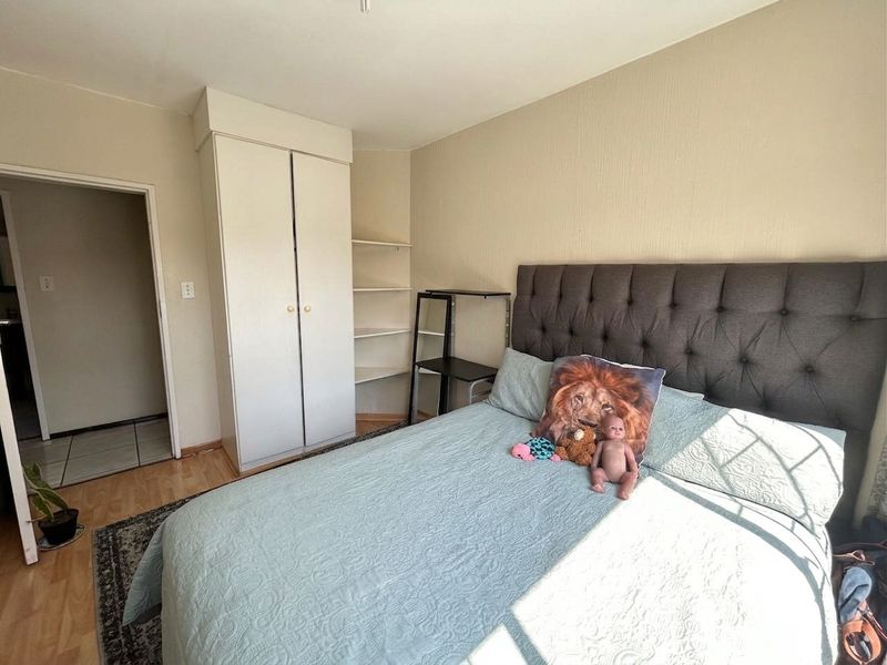 A bedroom featuring laminate flooring, a built-in wardrobe, and integrated shelving units, providing functional storage space.