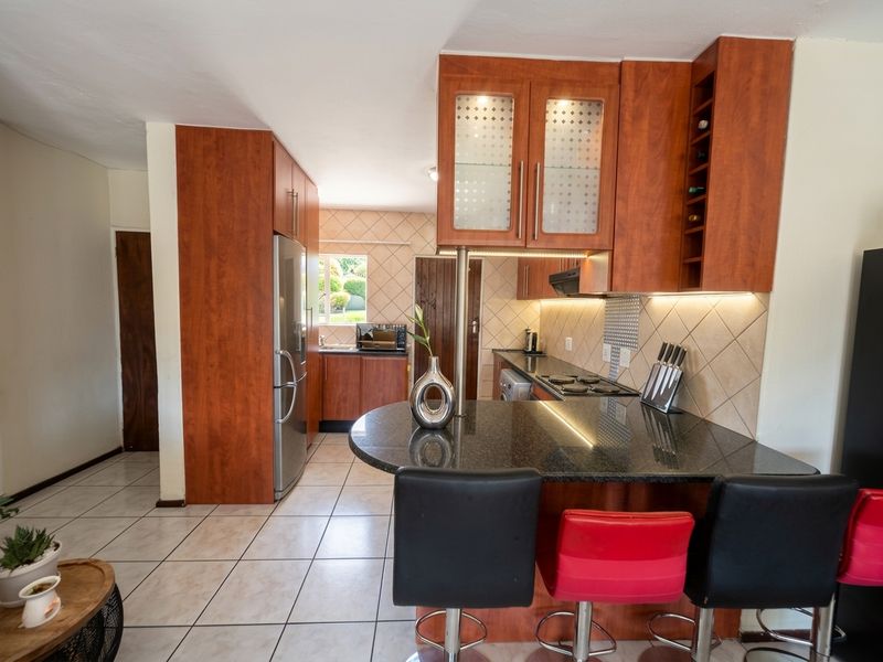 A functional kitchen featuring wood-finish cabinetry, granite countertops, a breakfast bar, and tiled flooring, offering a practical layout for daily cooking and dining.