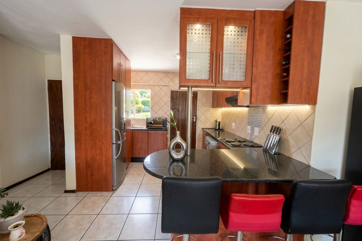 A functional kitchen featuring wood-finish cabinetry, granite countertops, a breakfast bar, and tiled flooring, offering a practical layout for daily cooking and dining.