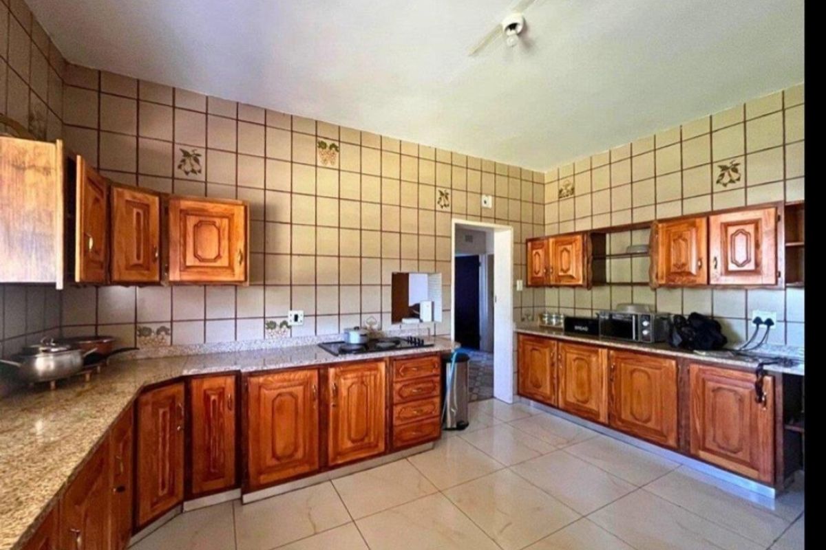 A functional kitchen featuring traditional wooden cabinetry, granite countertops, a built-in hob, and tiled wall finishes.