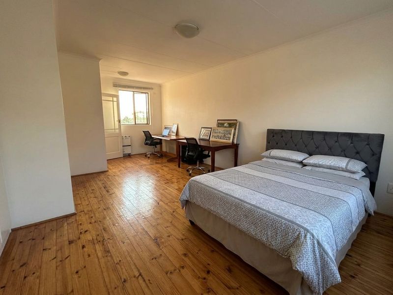 Spacious bedroom featuring polished timber flooring and natural light, offering a versatile layout suitable for a sleeping area and integrated home office space.