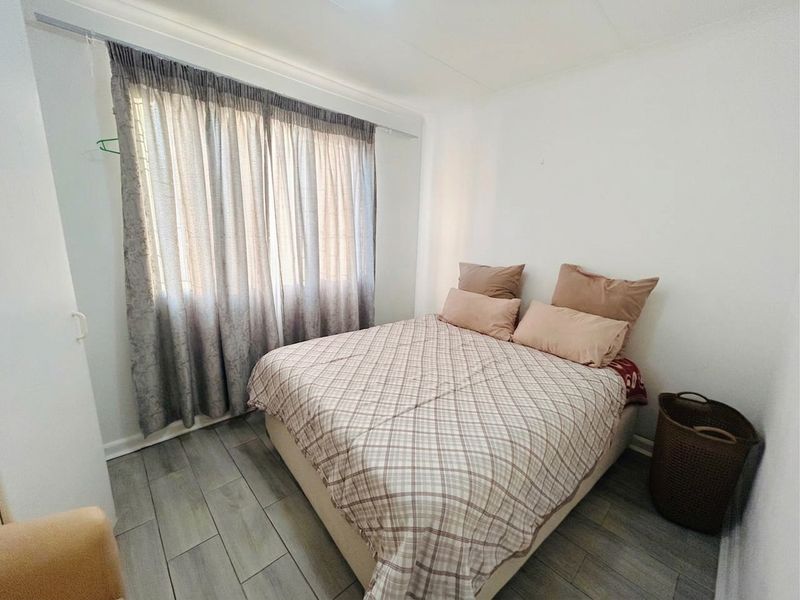 A functional bedroom featuring tiled flooring and neutral wall finishes, providing a clean and simple space.