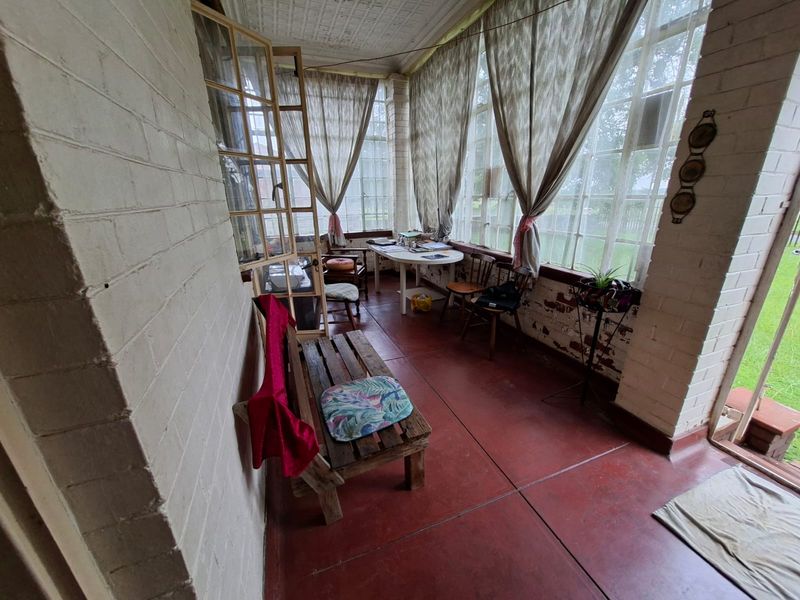 Enclosed sunroom or patio area featuring painted brick walls, large windows, and tiled flooring, offering a bright space with potential for renovation.
