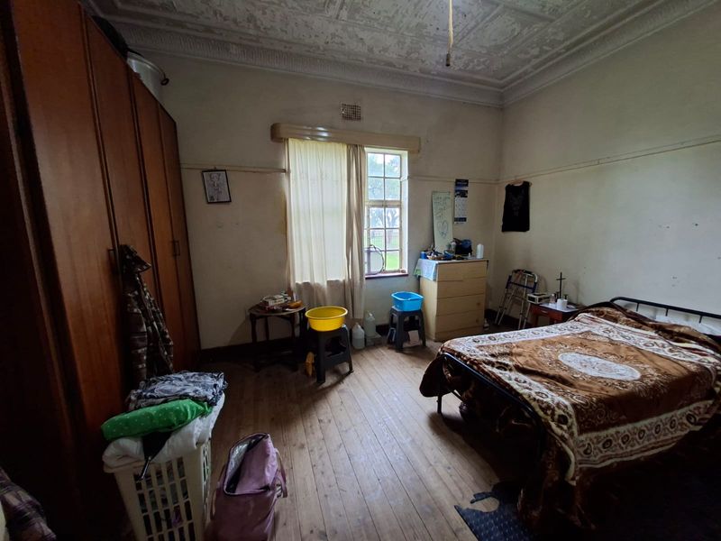 A bedroom featuring original timber flooring, an ornate ceiling, and a built-in wardrobe, requiring cosmetic updates to restore its character.
