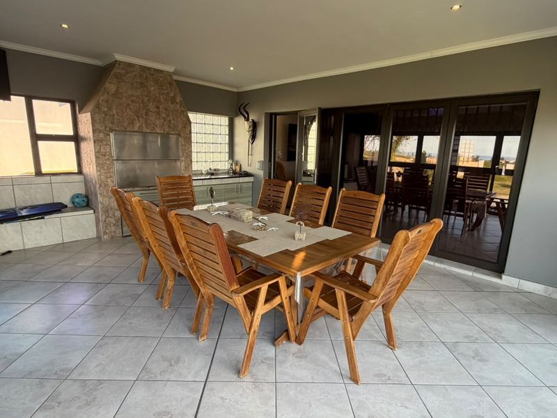Spacious covered patio featuring a built-in braai with stone cladding, tiled flooring, and large sliding doors providing seamless indoor-outdoor flow.